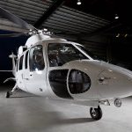 A white corporate helicopter in a hangar during dusk.